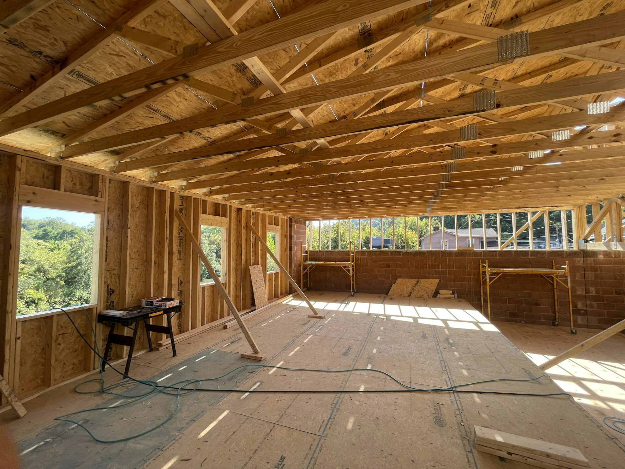 An unfinished interior of a building under construction with exposed wooden framing and tools.