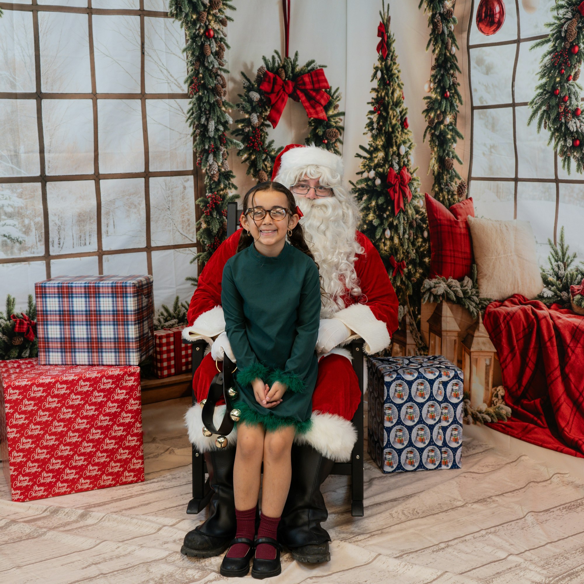A girl sitting on Santa Claus's lap, surrounded by Christmas decorations and presents.