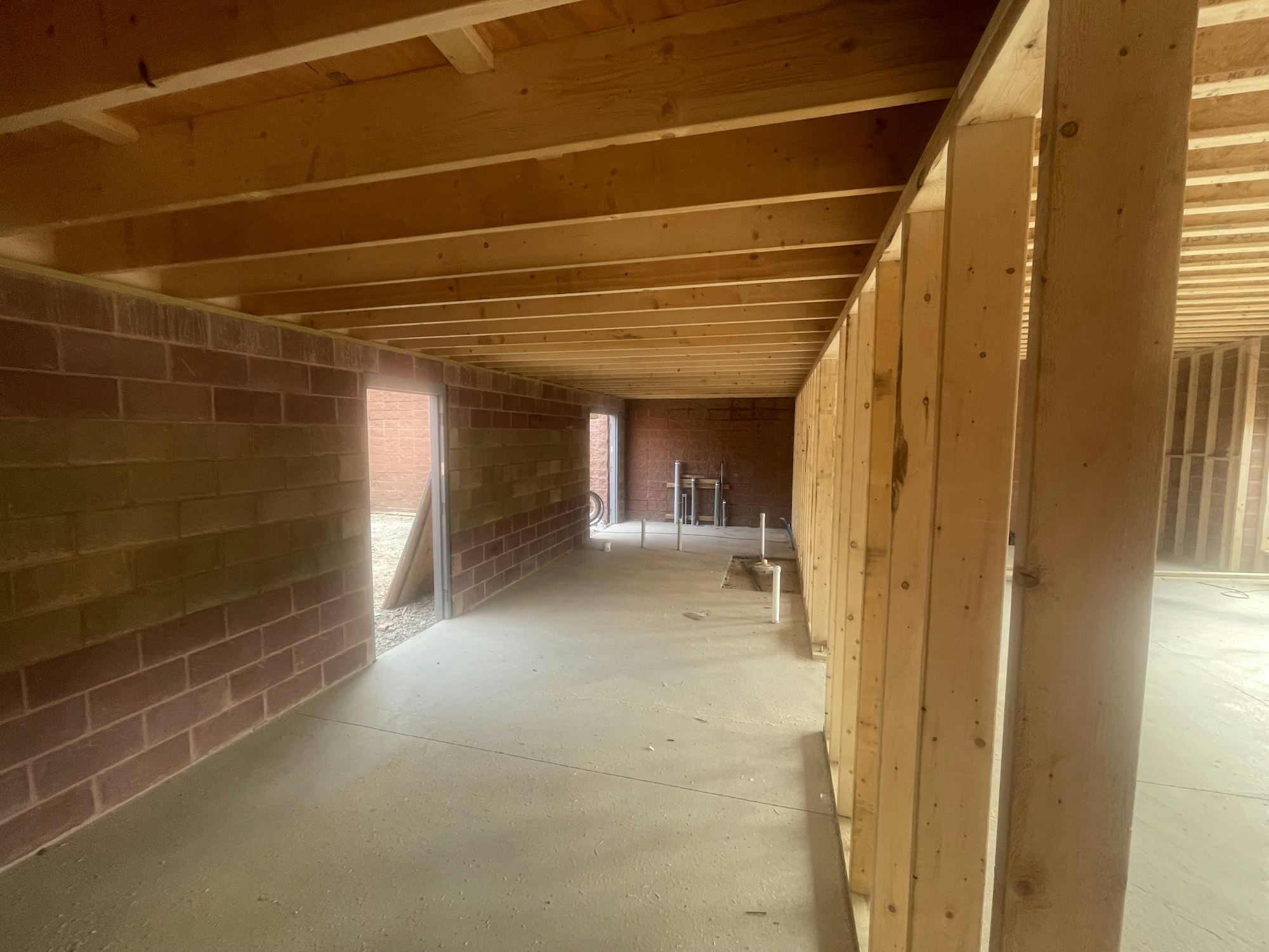 An unfinished interior space with exposed wooden beams and brick walls.