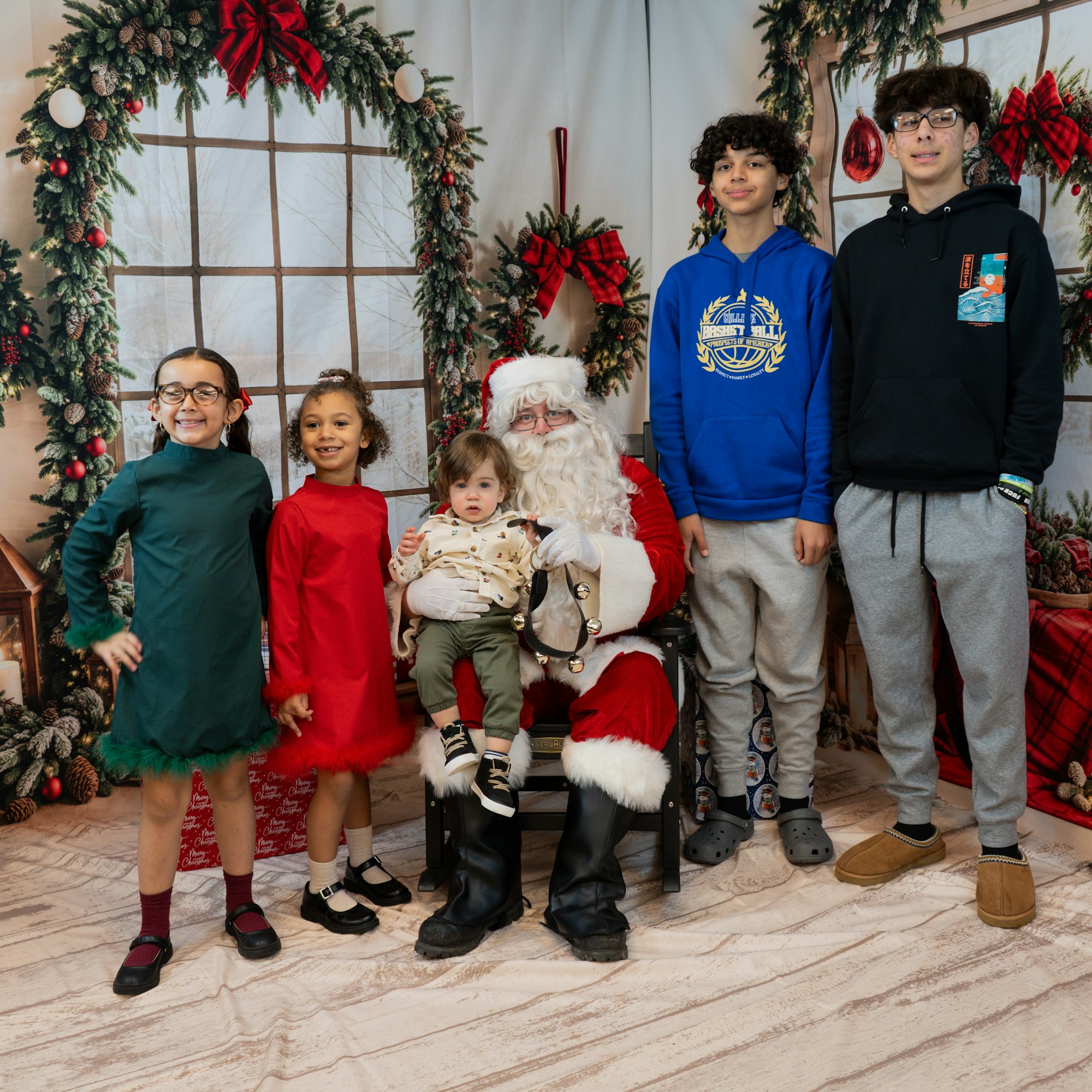 A group of kids posing with Santa in a festive setting with holiday decorations.