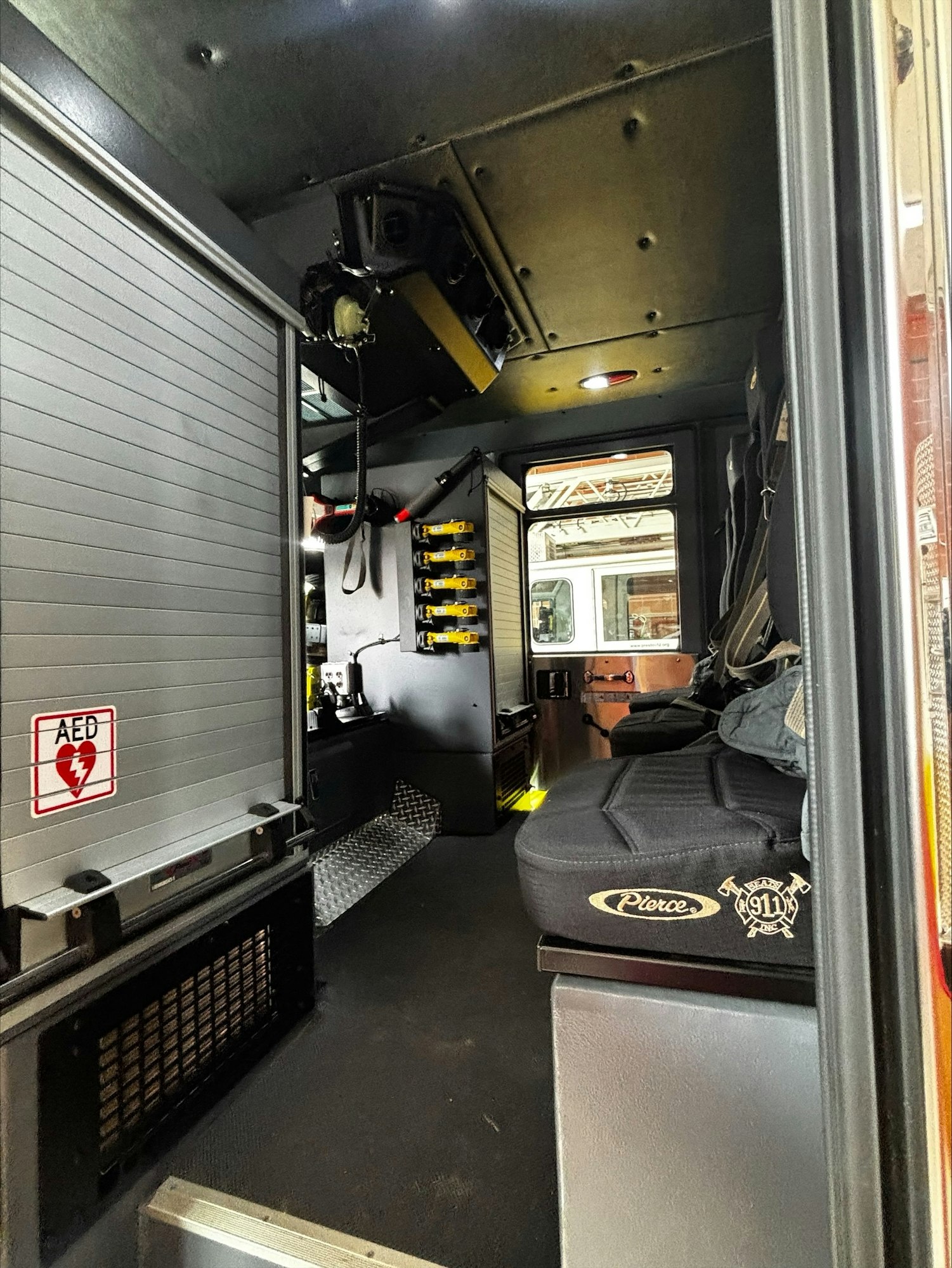 The image shows the interior of a fire truck, featuring seating, equipment shelving, and emergency gear.
