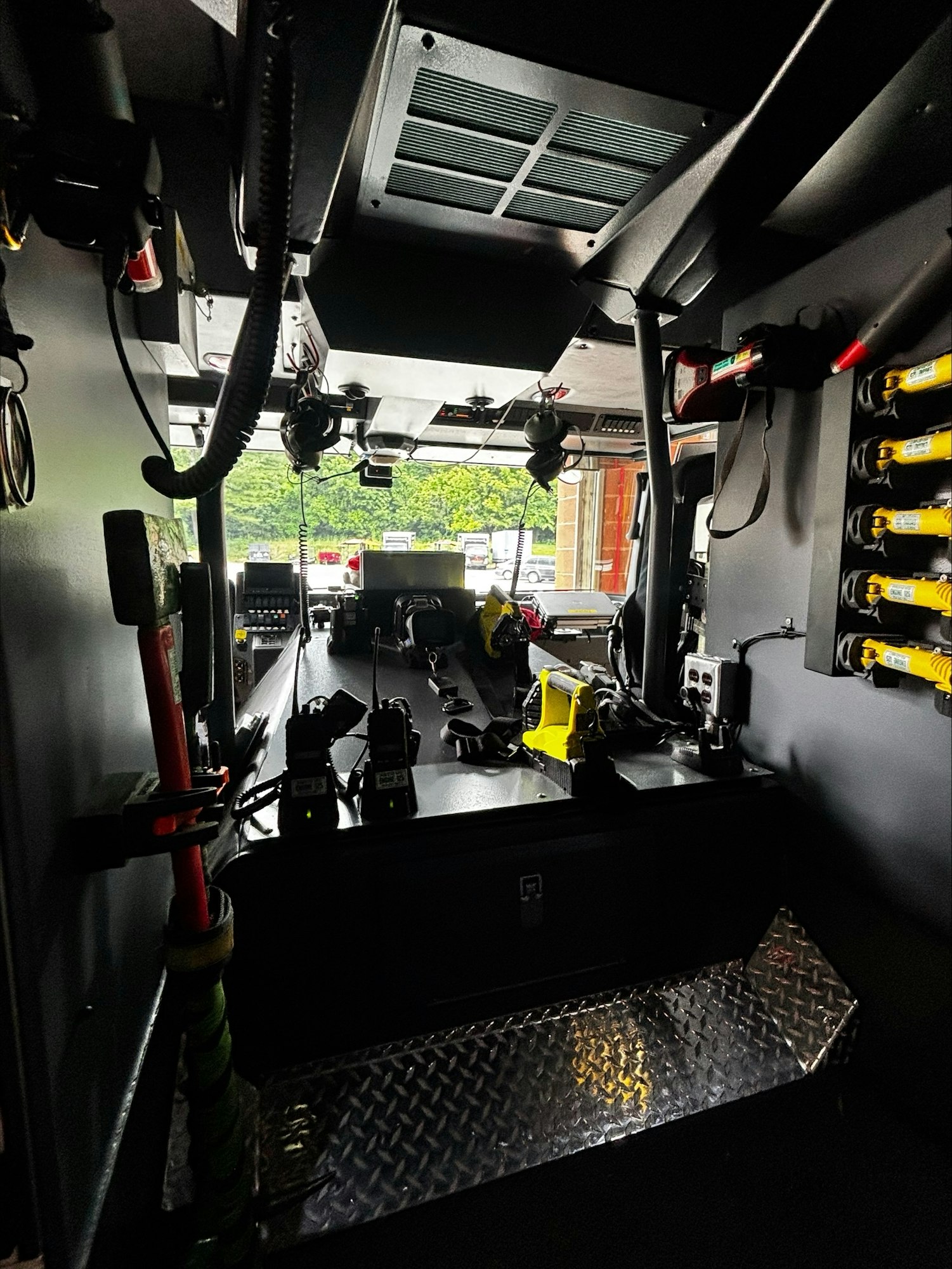 The image shows the interior of a vehicle, likely an emergency vehicle, equipped with communication devices and storage areas.
