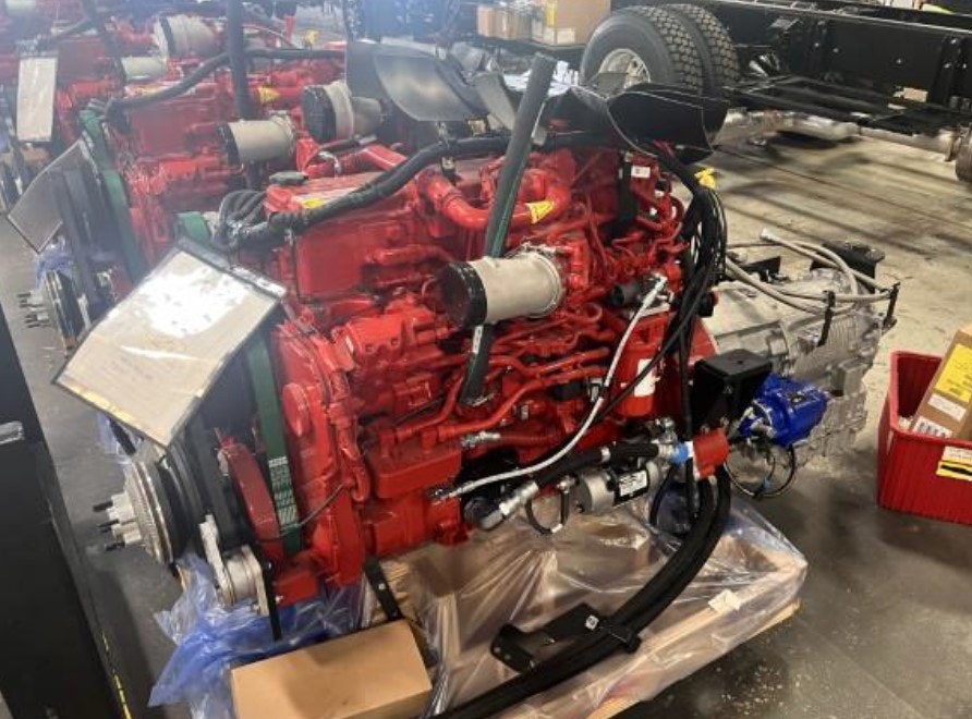 Red engines on a workshop floor, attached to chassis frames. Various tools and boxes are visible around.