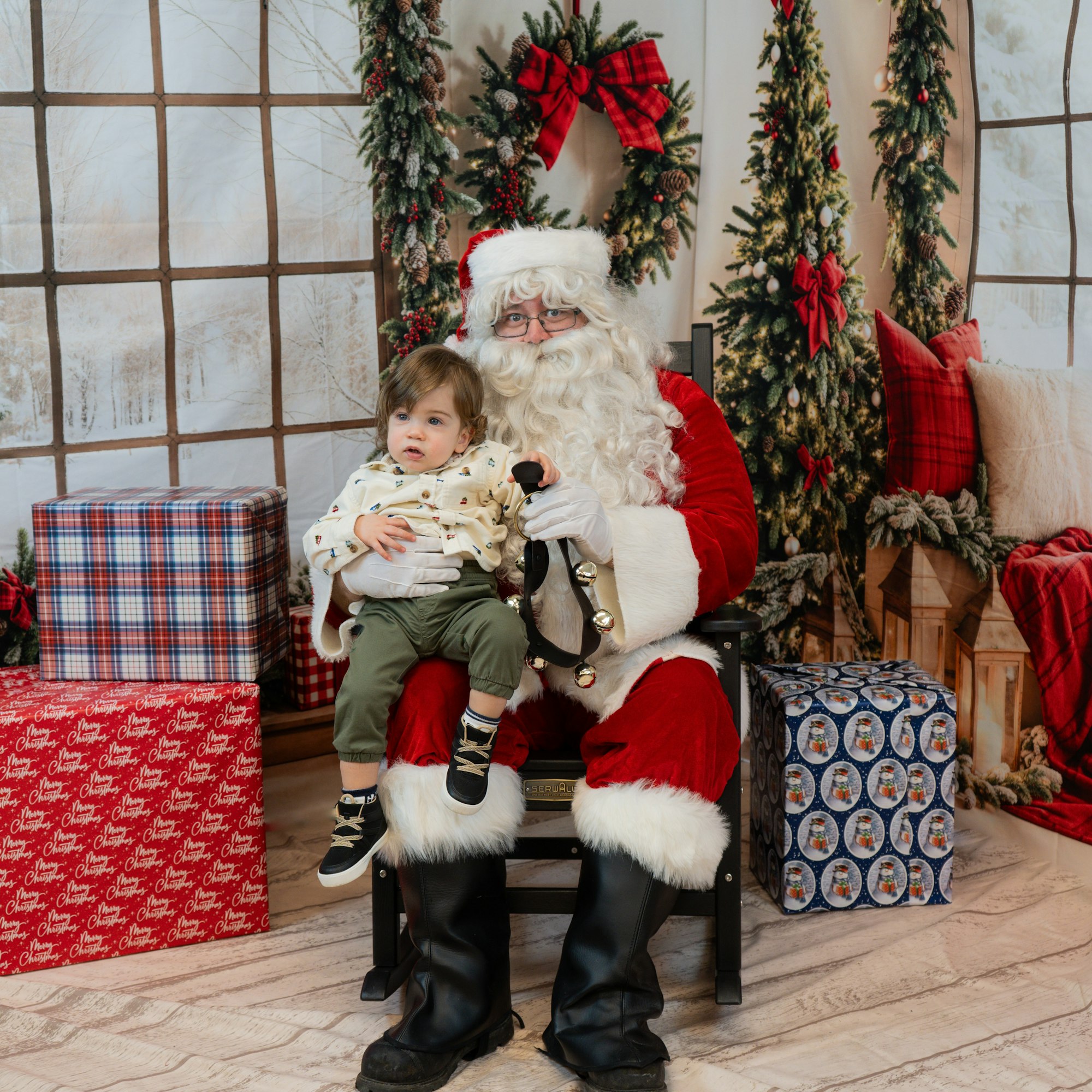 Child sitting on Santa's lap surrounded by Christmas decor and gifts.