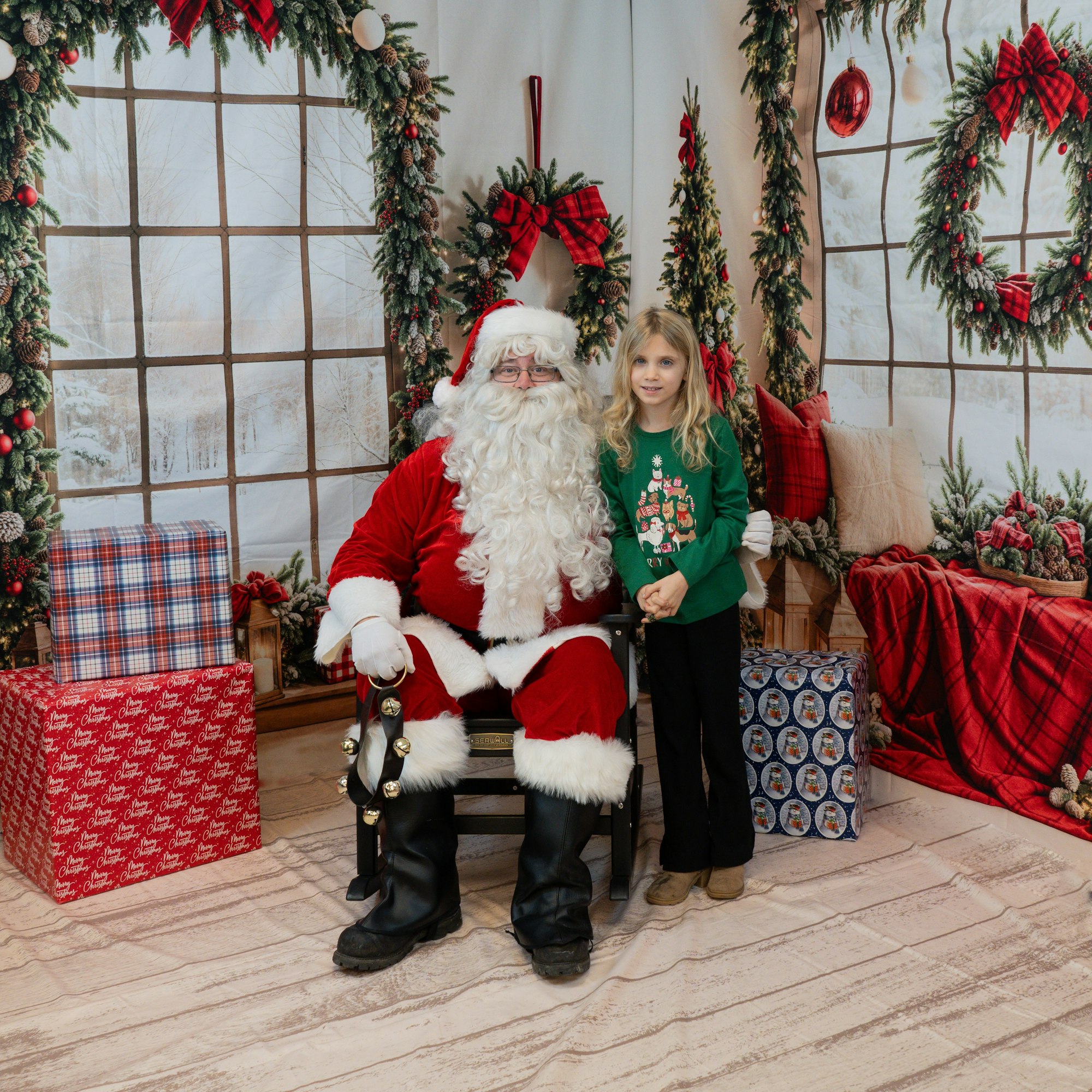 Santa sitting with a child in a festive setting, surrounded by Christmas decorations and wrapped gifts.