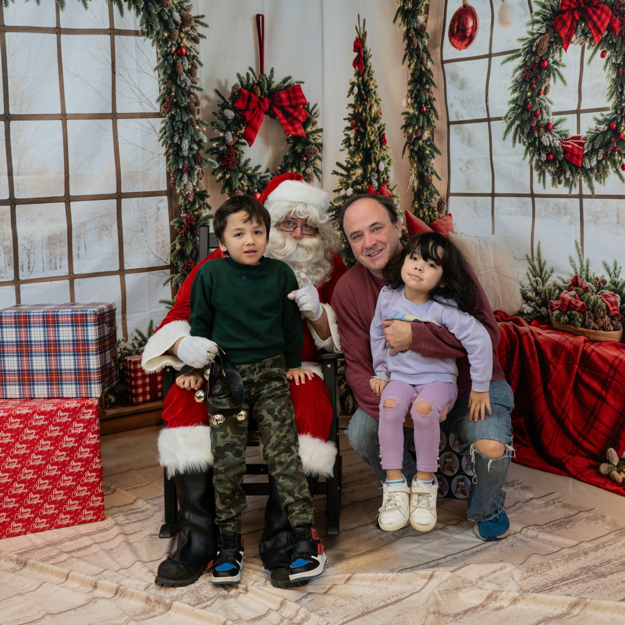 A festive Christmas scene with Santa Claus, a family, and holiday decorations around them.