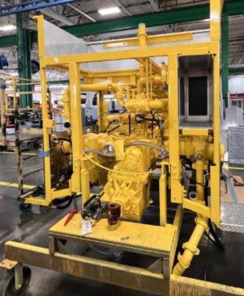 Yellow industrial machinery in a workshop setting, surrounded by pipes and mechanical components.