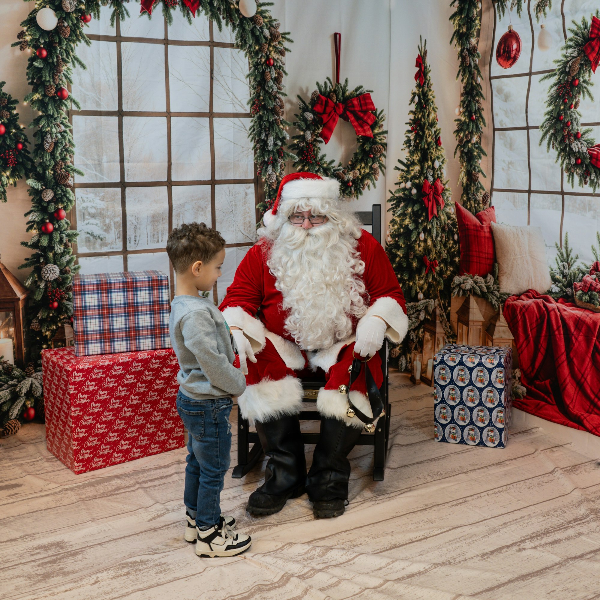 A child standing with Santa Claus, surrounded by Christmas decorations and presents.