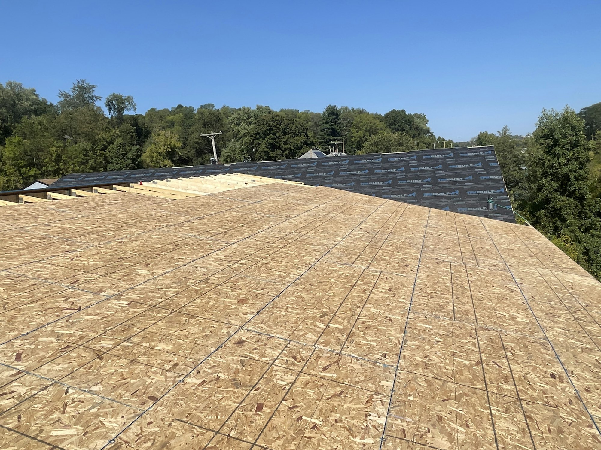 A partially completed house roof with plywood sheathing and underlayment.