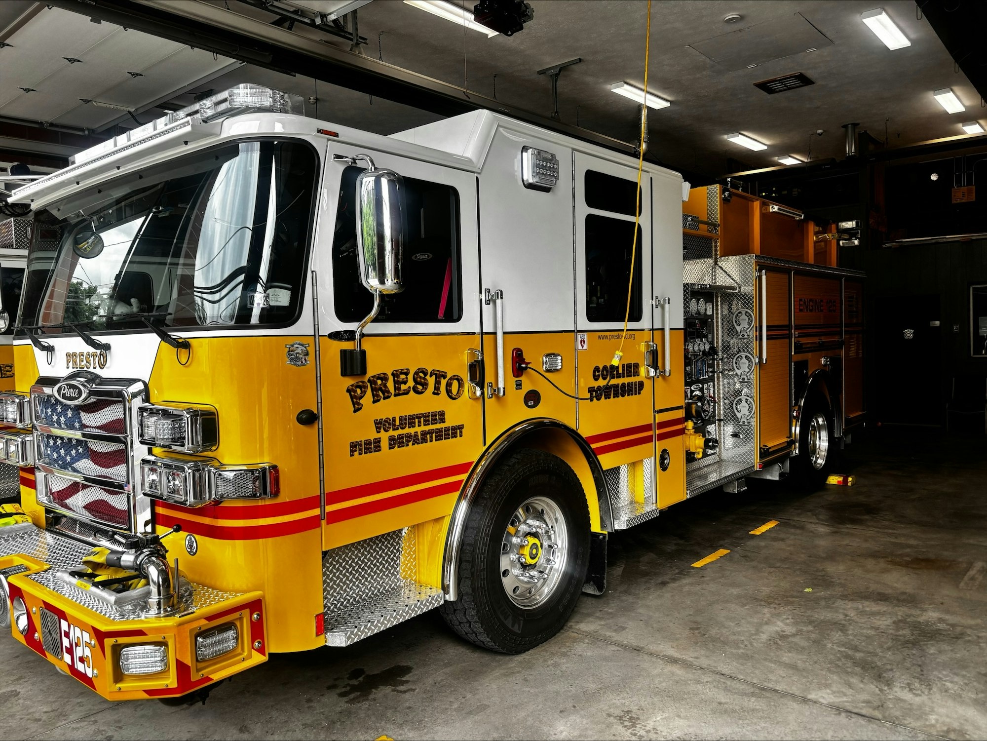 A bright yellow fire truck labeled "Presto Volunteer Fire Department" parked inside a fire station.