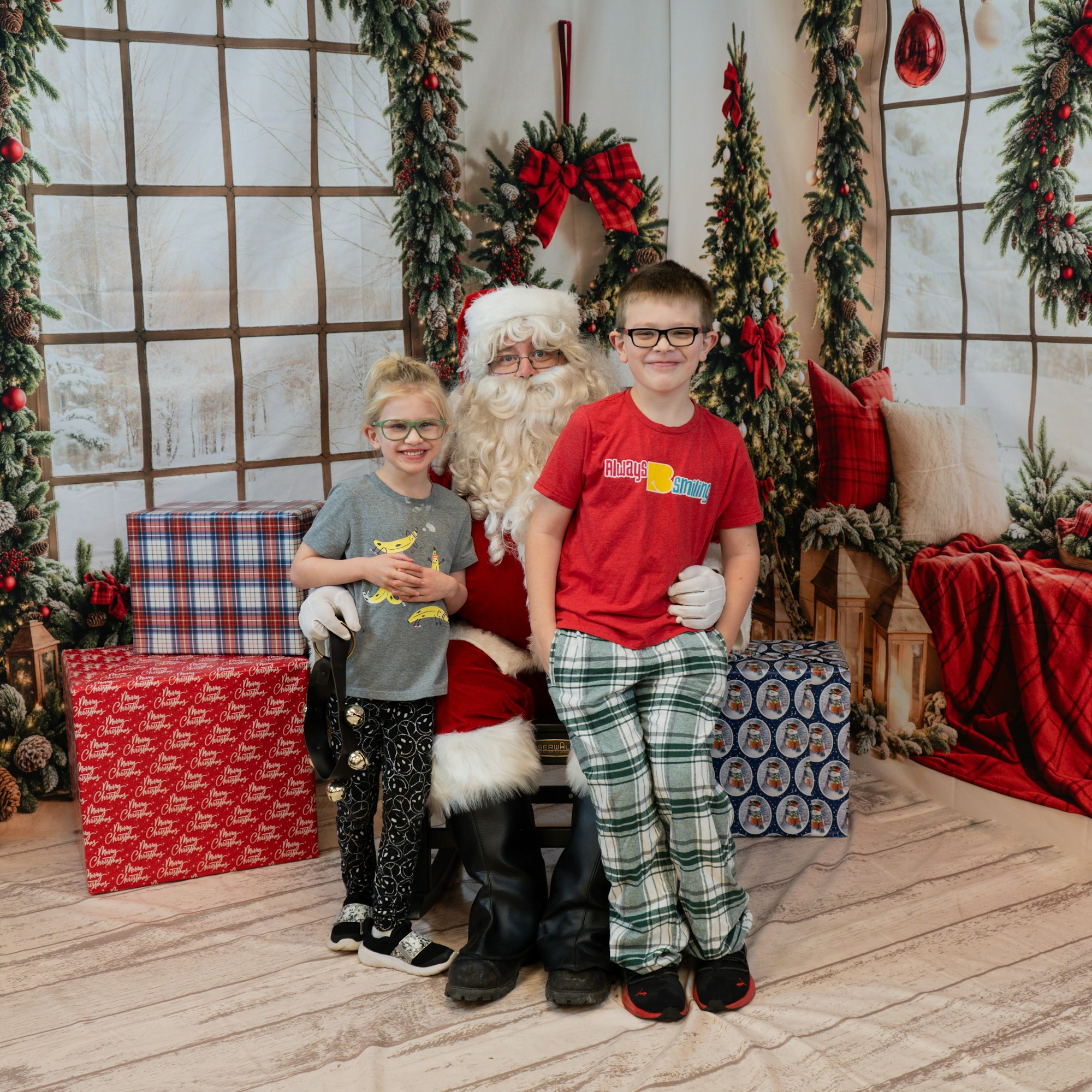 Two kids posing with Santa Claus, surrounded by Christmas decorations and presents.