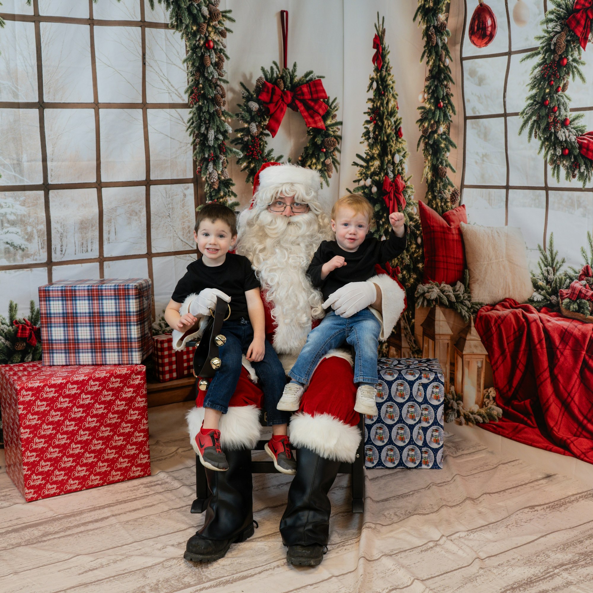 Santa with two kids on his lap, surrounded by gifts and holiday decor.