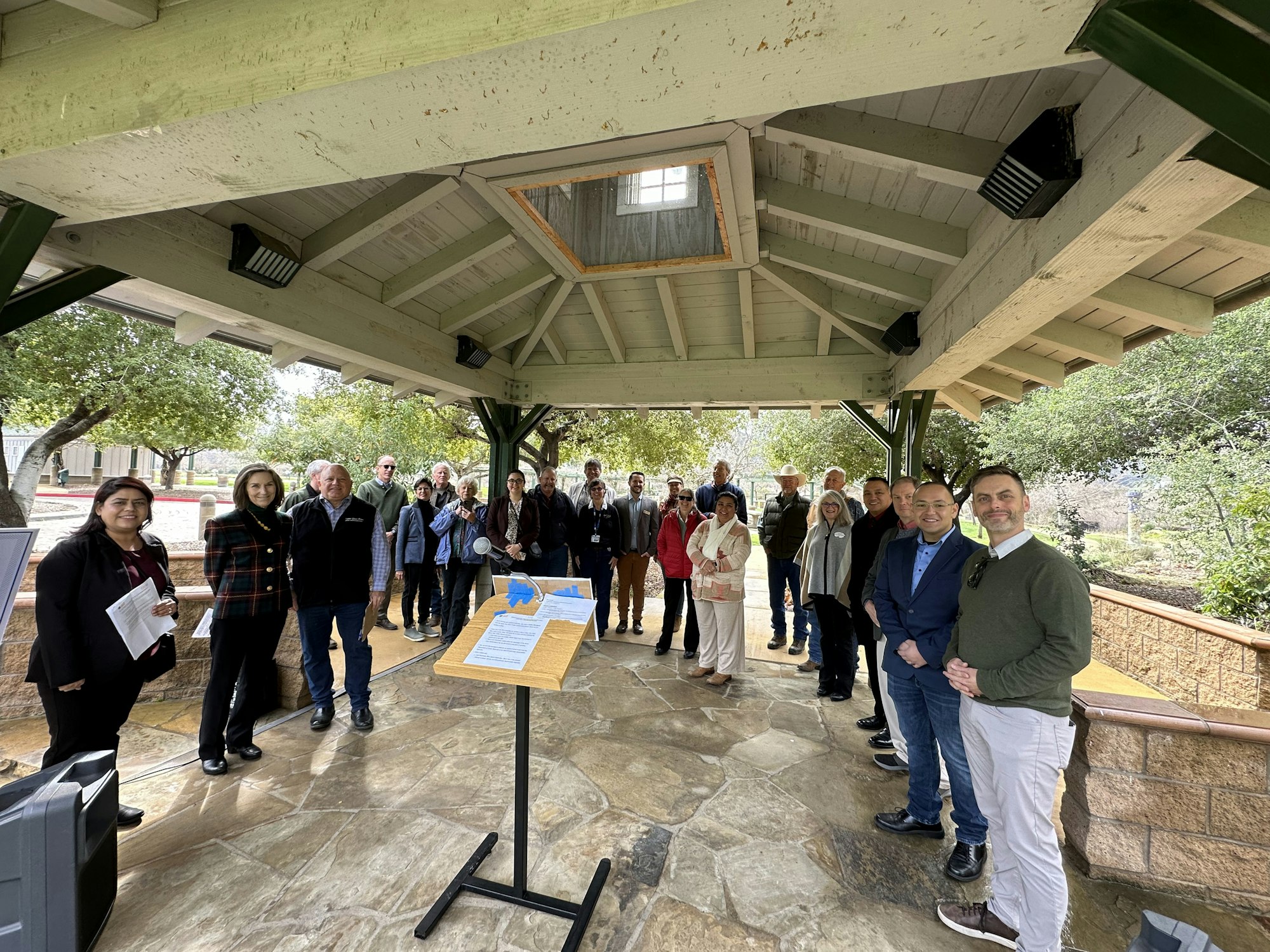 A group of people gathered under a covered outdoor structure, possibly for an event or meeting.