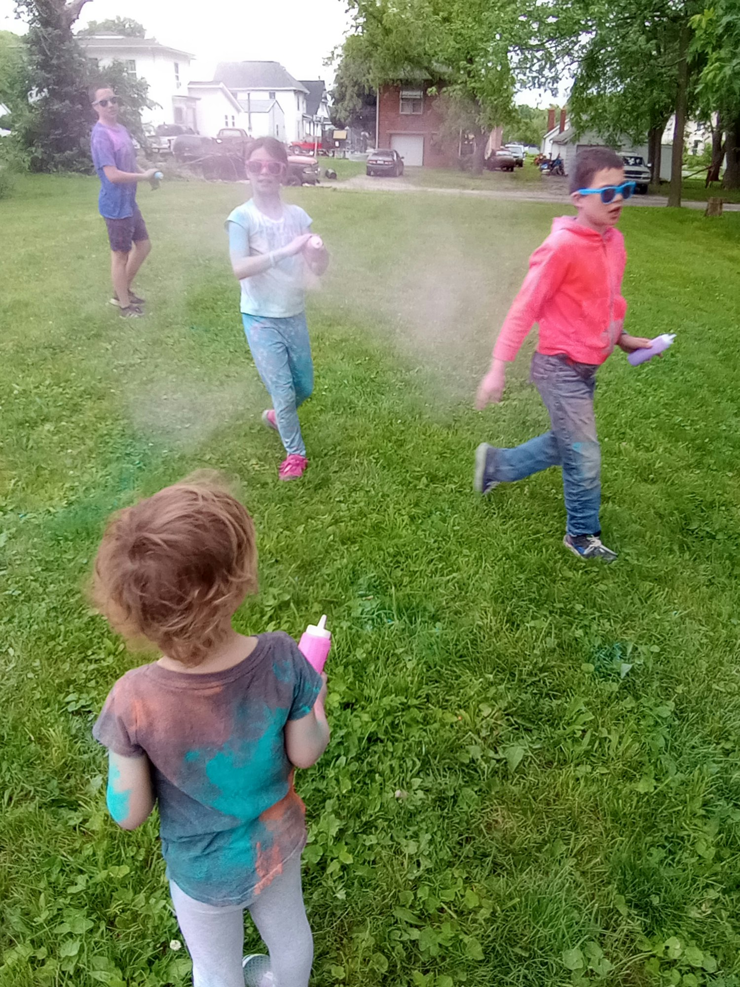 People playing with colored powder in a grassy field.