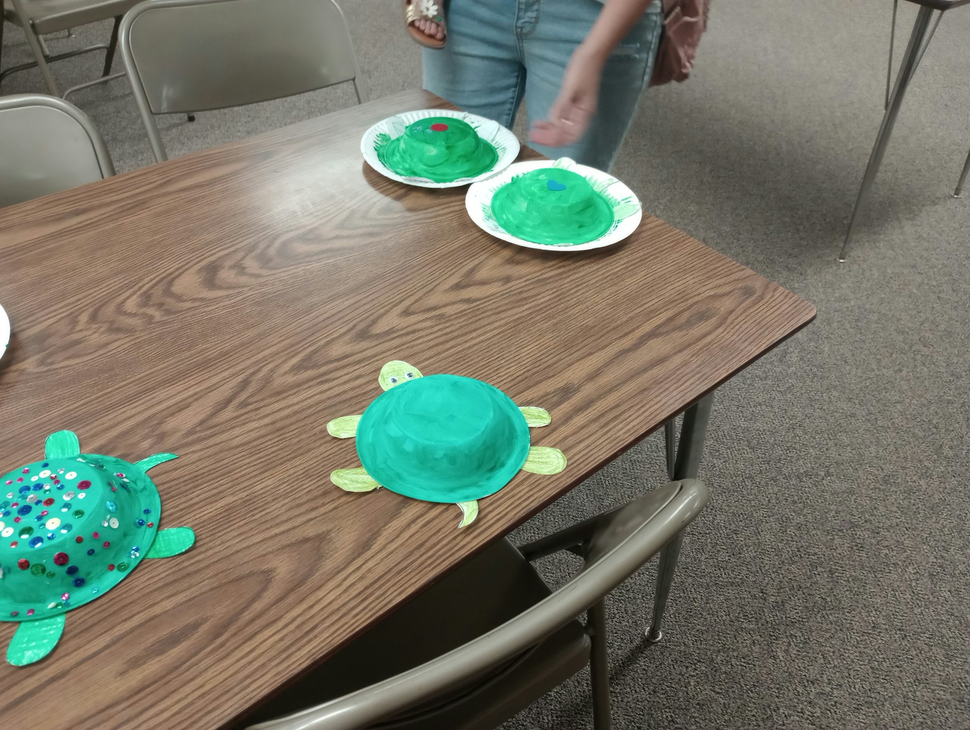 Craft turtles made from painted bowls and paper plates on a table.