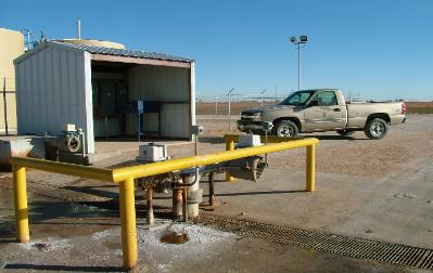 Truck parked by a barn near a yellow pipe.