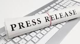 A rolled-up document reading "PRESS RELEASE" on a computer keyboard.
