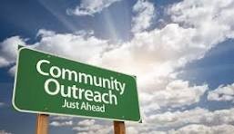 Green road sign saying "Community Outreach Just Ahead" against a blue sky with clouds.