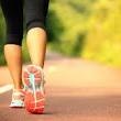 Close-up of a person's legs wearing sneakers, walking on a path.