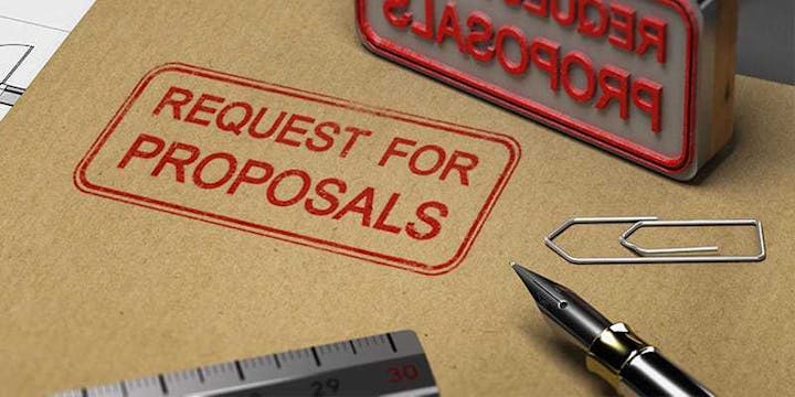 "Request for Proposals" stamp, pen, paper clip, and ruler on a brown envelope.