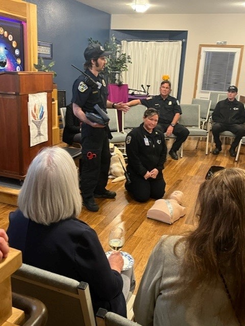 A first aid demonstration with CPR dummies and attendees in a room, led by a person in uniform.