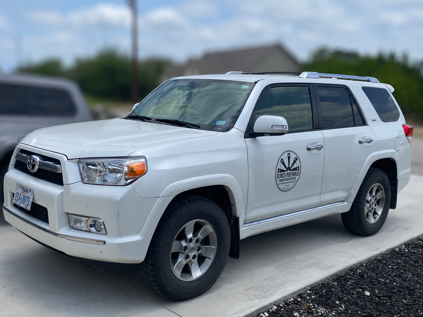 A white Toyota SUV with a logo for a groundwater service, parked on a driveway.