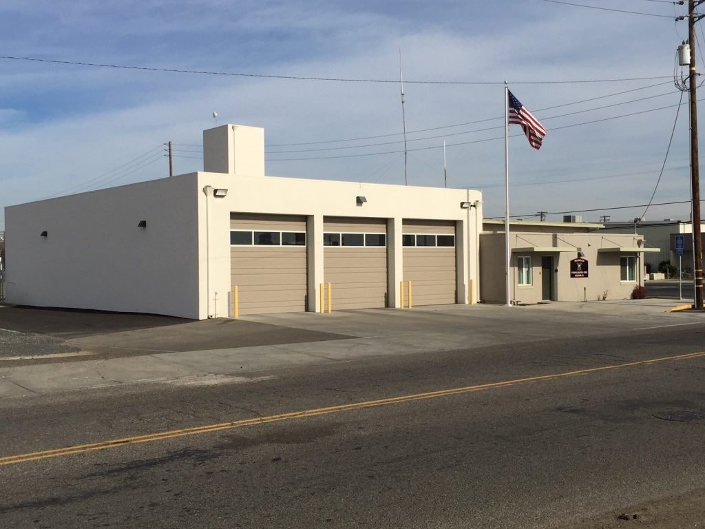 A small building with garage doors and an American flag flying on a clear day.