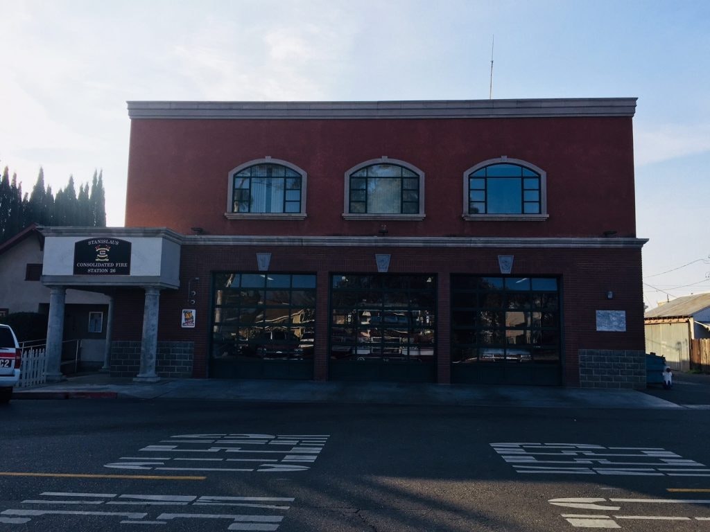 A red building with arched windows and a sign indicating "Stanislaus Consolidated Fire Station 26."