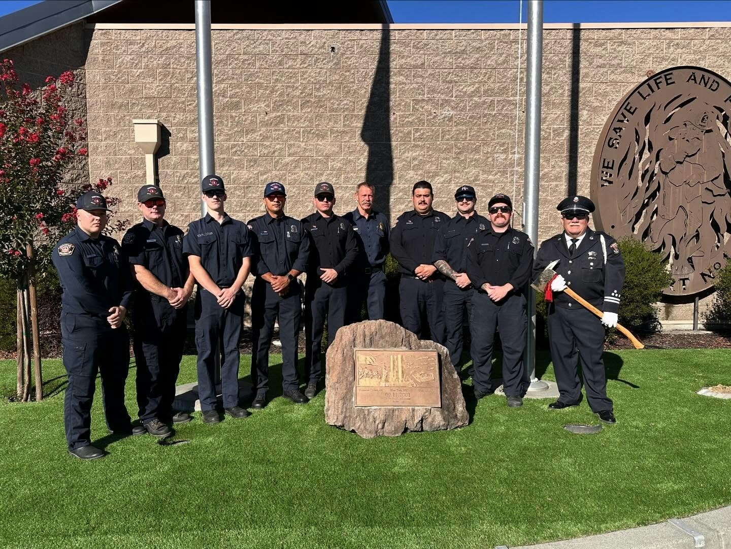 A group of firefighters poses together in front of a monument, showcasing teamwork and service.