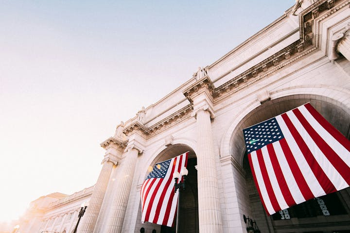 Architectural building with large hanging American flags. Clear sky.