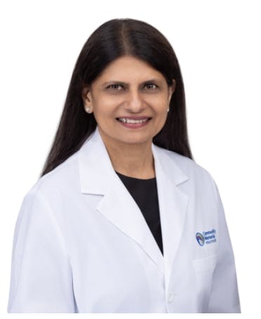A person in a white lab coat, smiling, likely a medical professional. The background is plain white.