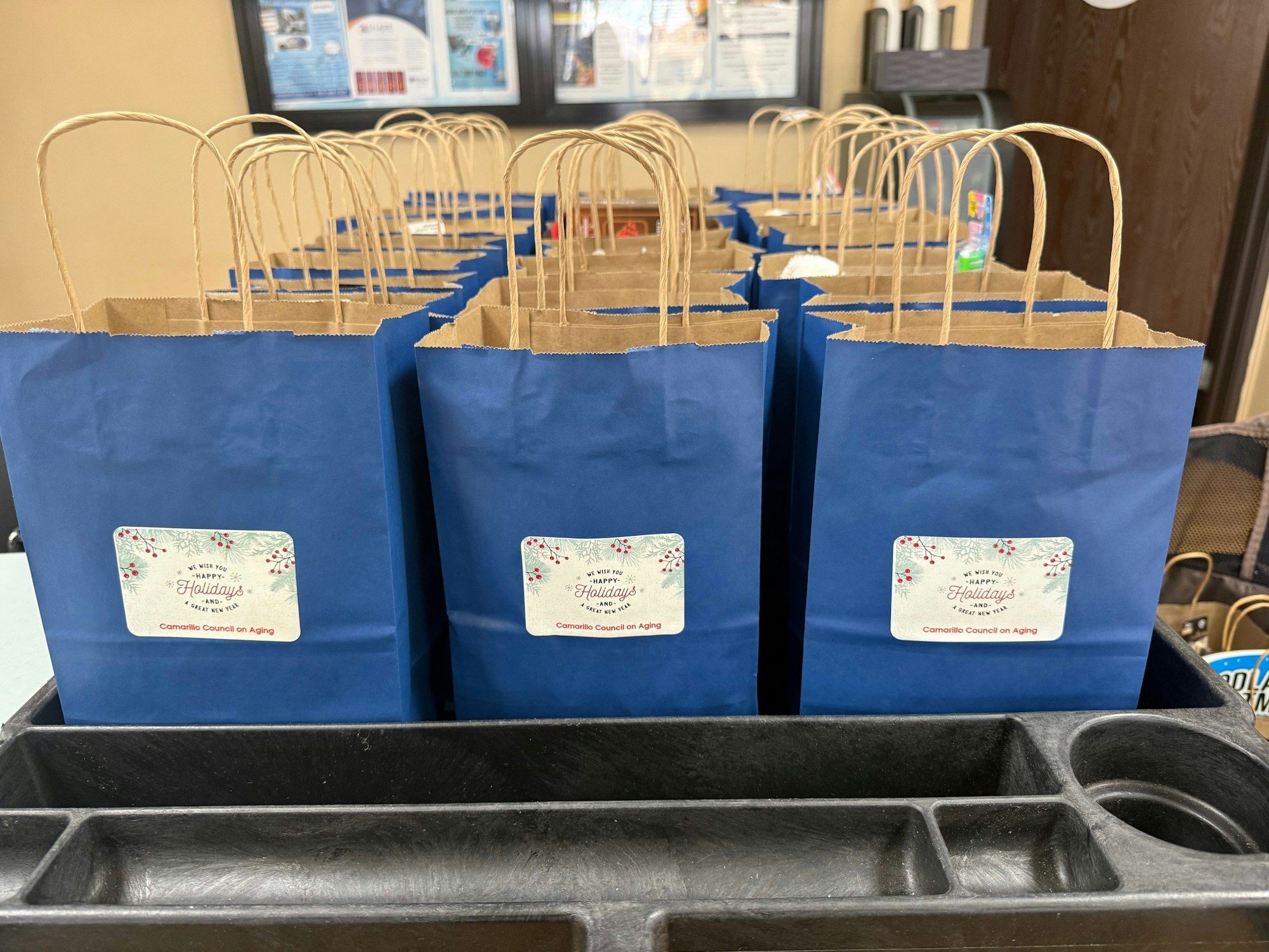Several blue gift bags with "Council on Aging" labels, arranged neatly in a row on a table.