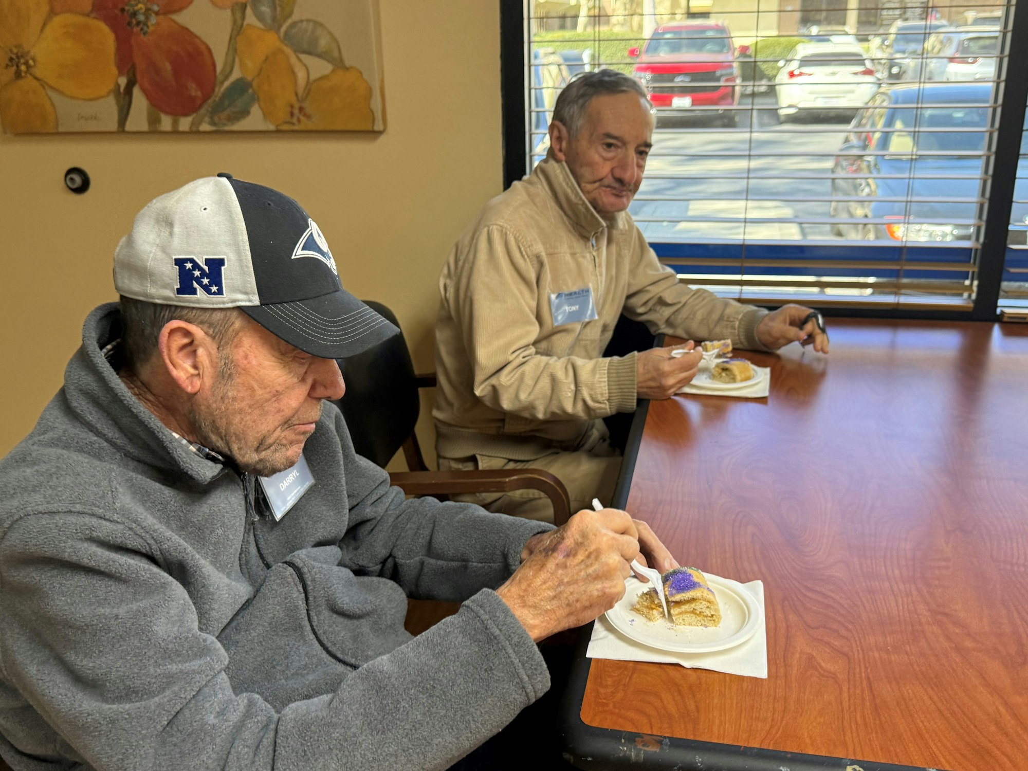 Two people sitting at a table, eating cake.