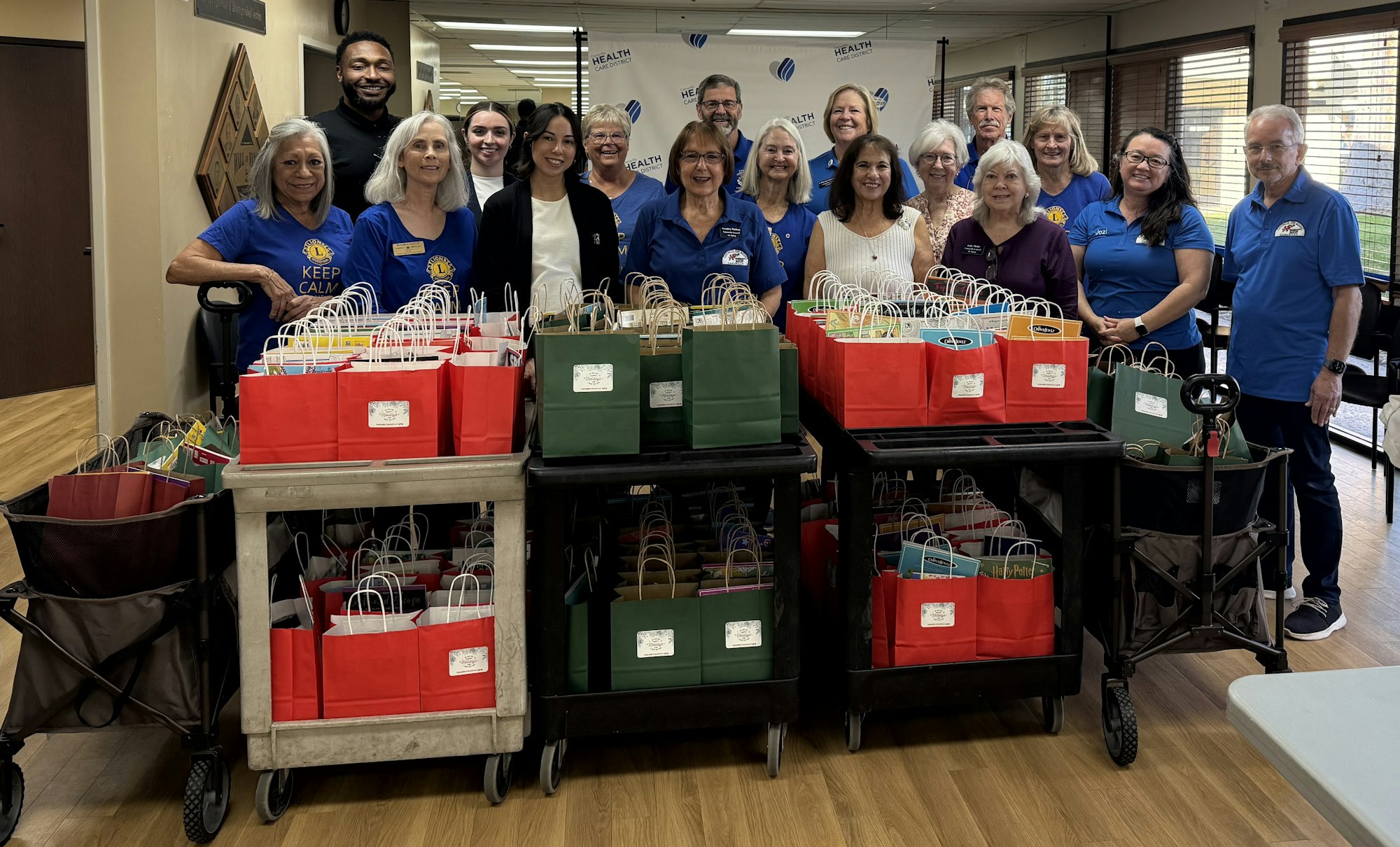 A group of volunteers poses with colorful gift bags at a community event, promoting support and togetherness.