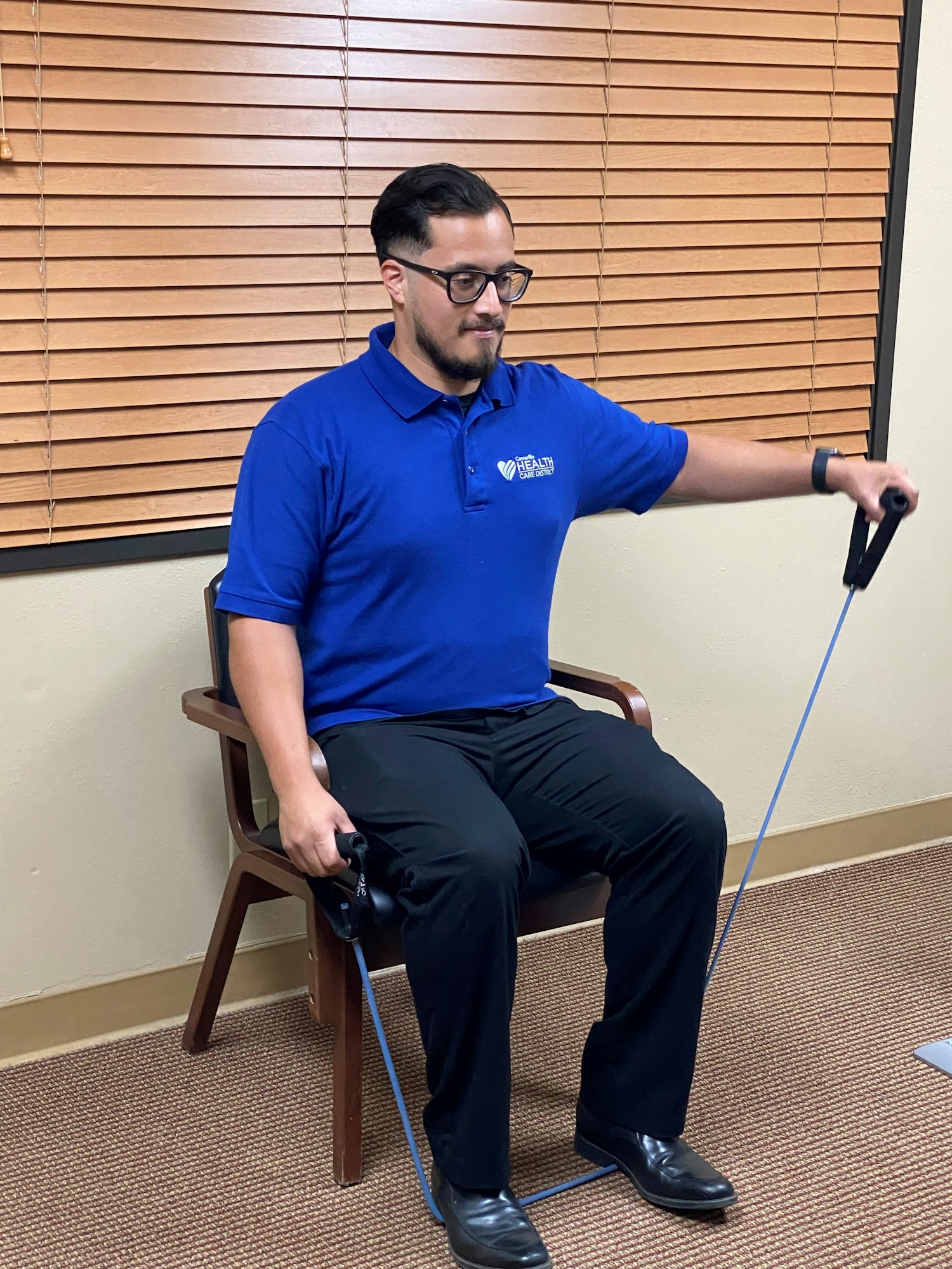 A man sitting on a chair exercising with a resistance band.