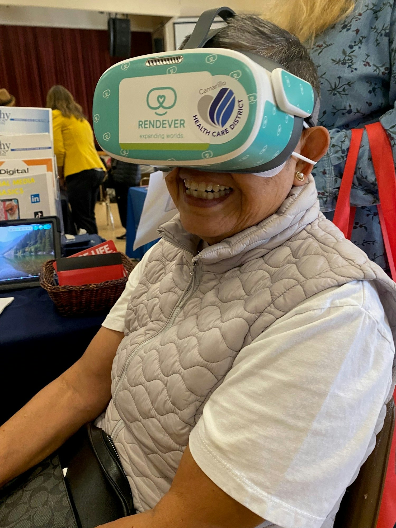 Person wearing a VR headset with the logo "Rendever," smiling indoors.