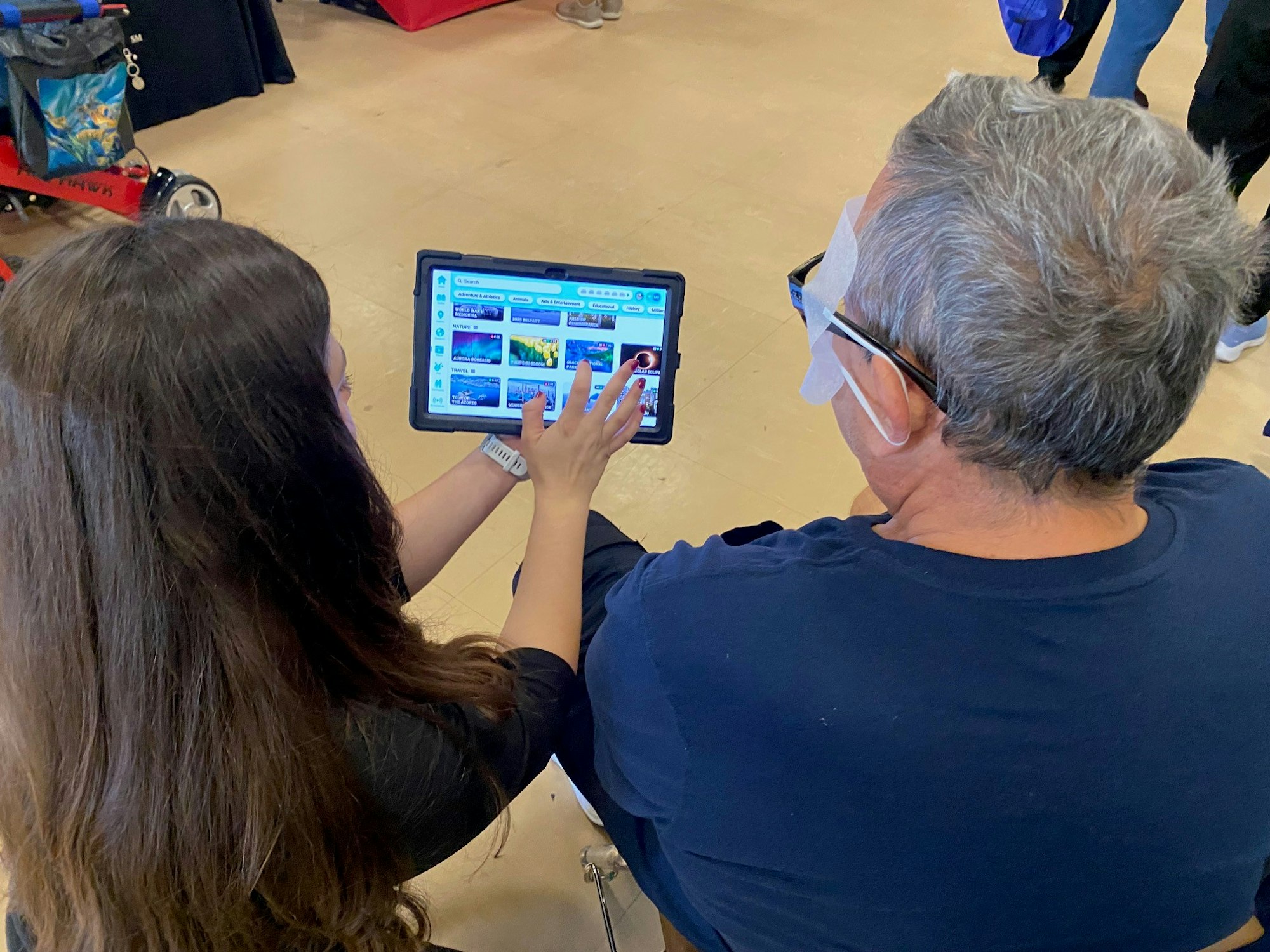 Two people are looking at a tablet screen while indoors, possibly discussing content.