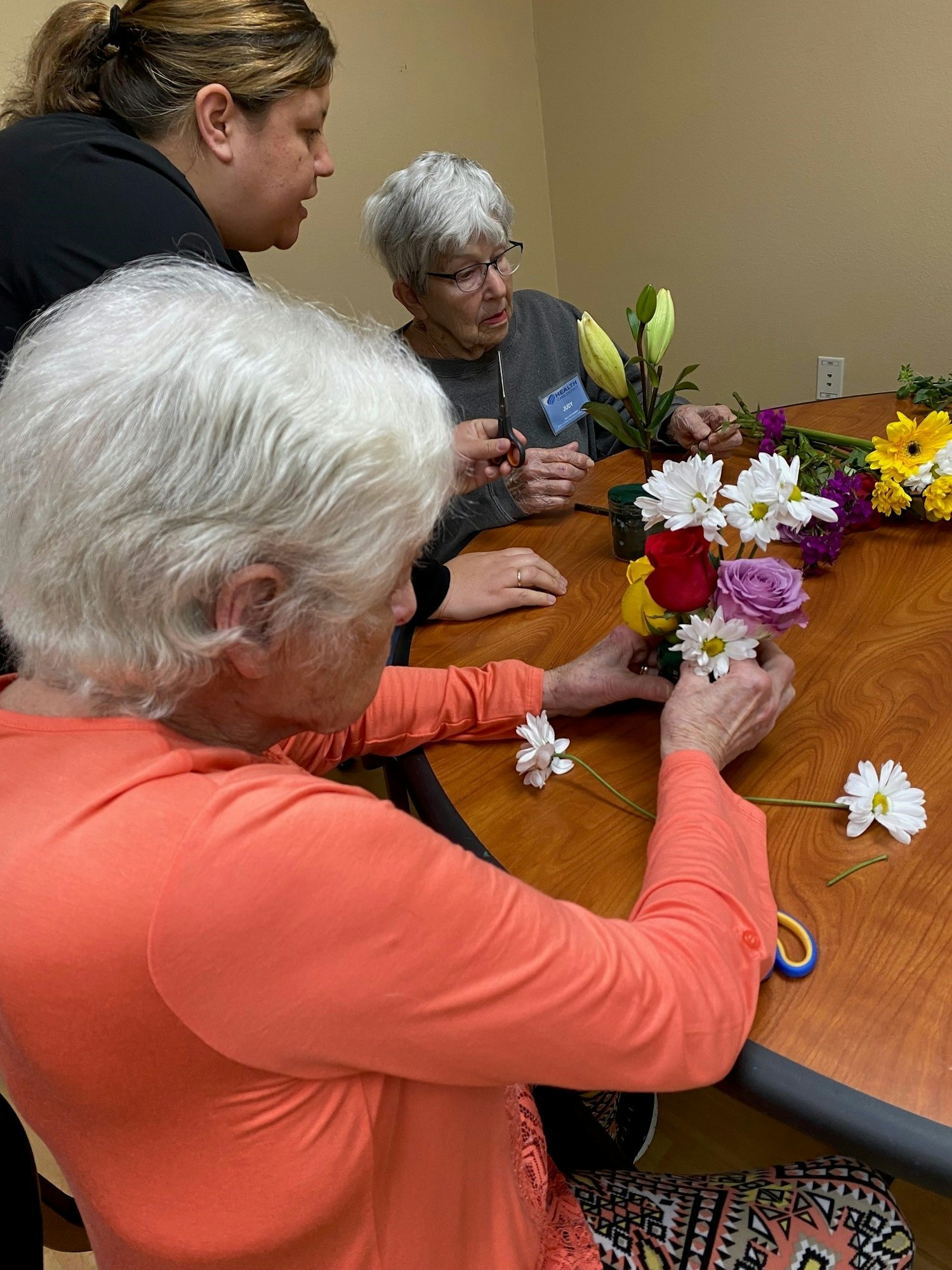 May contain: flower, flower arrangement, plant, flower bouquet, adult, male, man, person, petal, furniture, table, female, woman, ikebana, accessories, and glasses