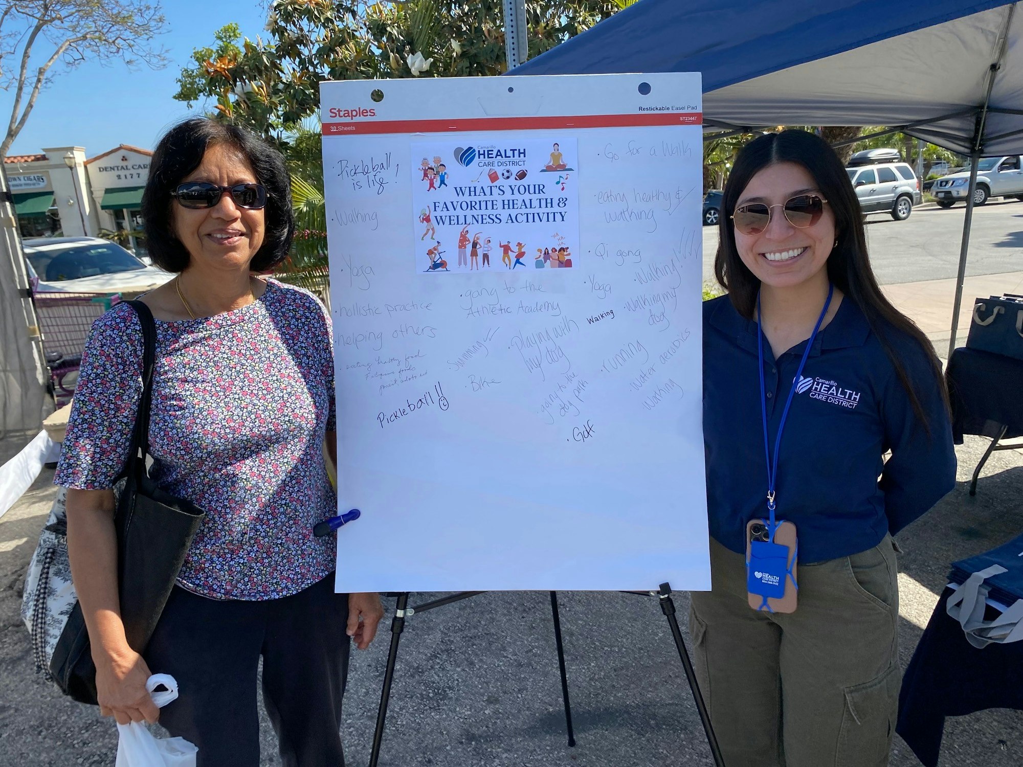 Two women beside a sign asking for favorite health and wellness activities, with various activities listed by participants.