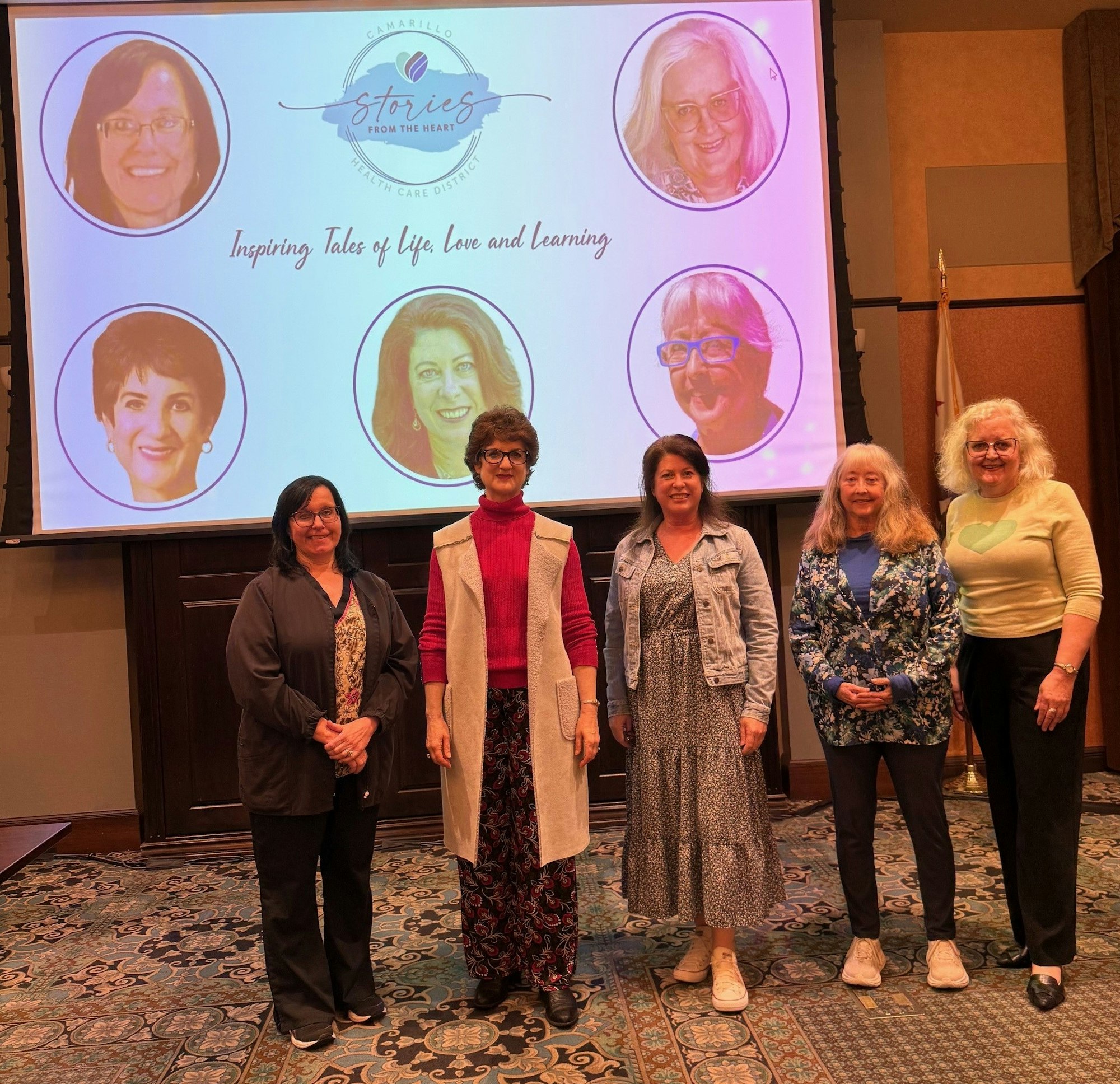 Five women stand in front of a screen displaying "Stories from the Heart" with photos and text saying "Inspiring Tales of Life, Love and Learning."
