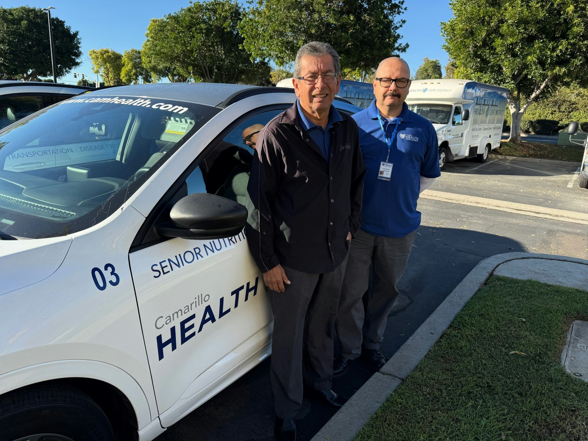 Two men stand by a vehicle labeled "Camarillo Health," likely associated with senior nutrition and transportation services.