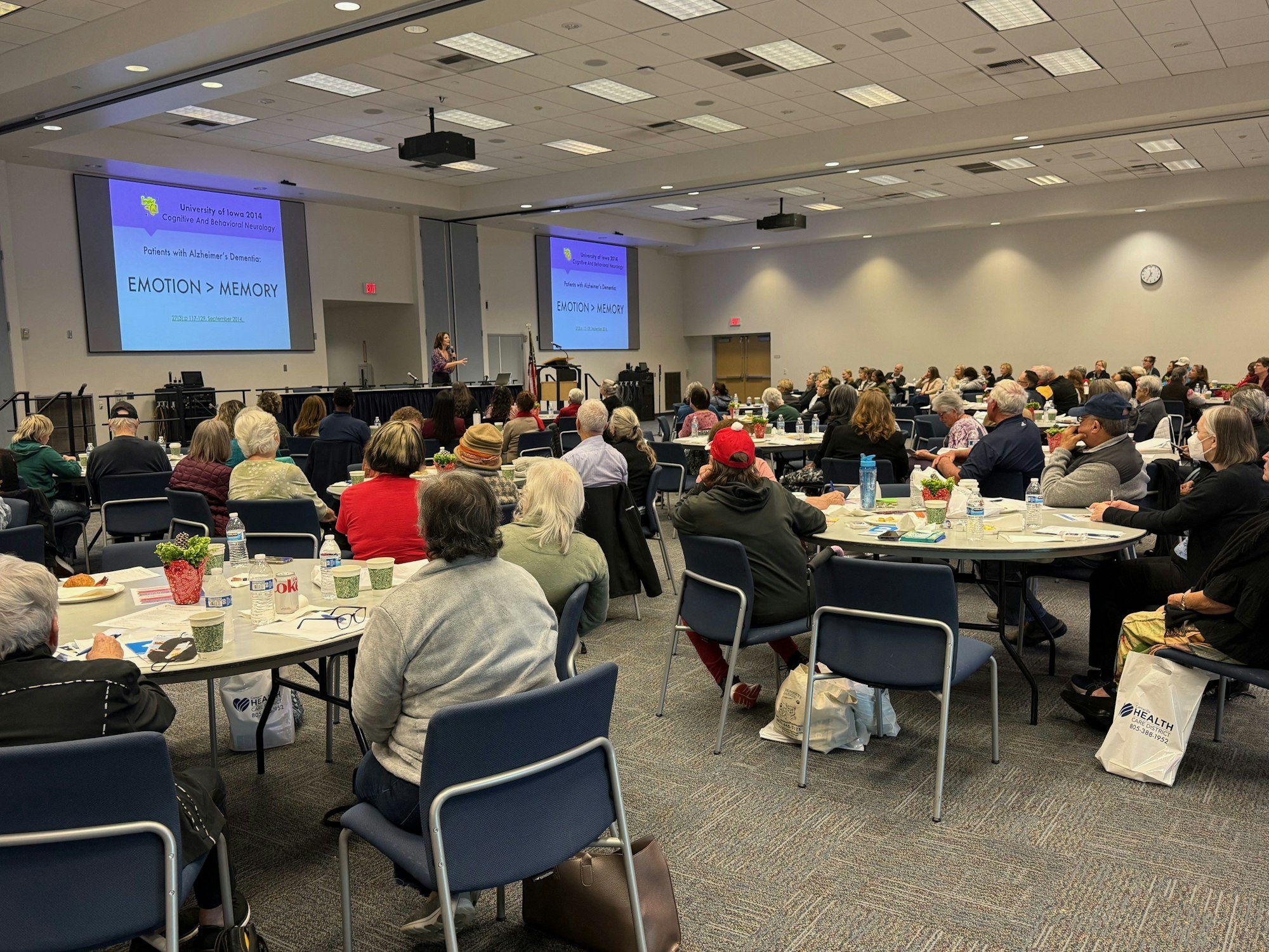 A large audience attends a presentation on "Emotion > Memory" related to Alzheimer’s at a conference.