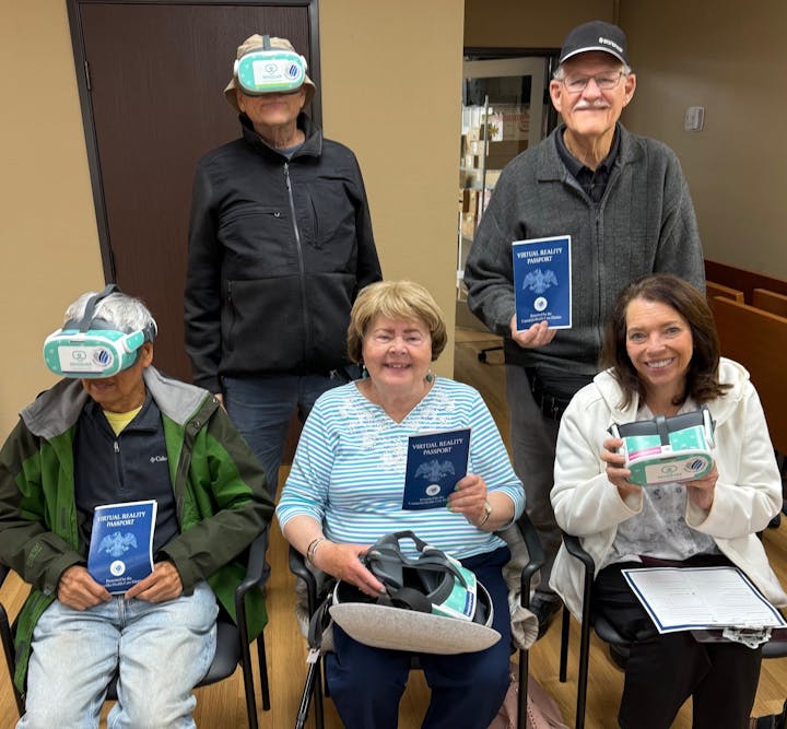 Five people with virtual reality glasses and "Virtual Reality Passport" booklets, smiling indoors.