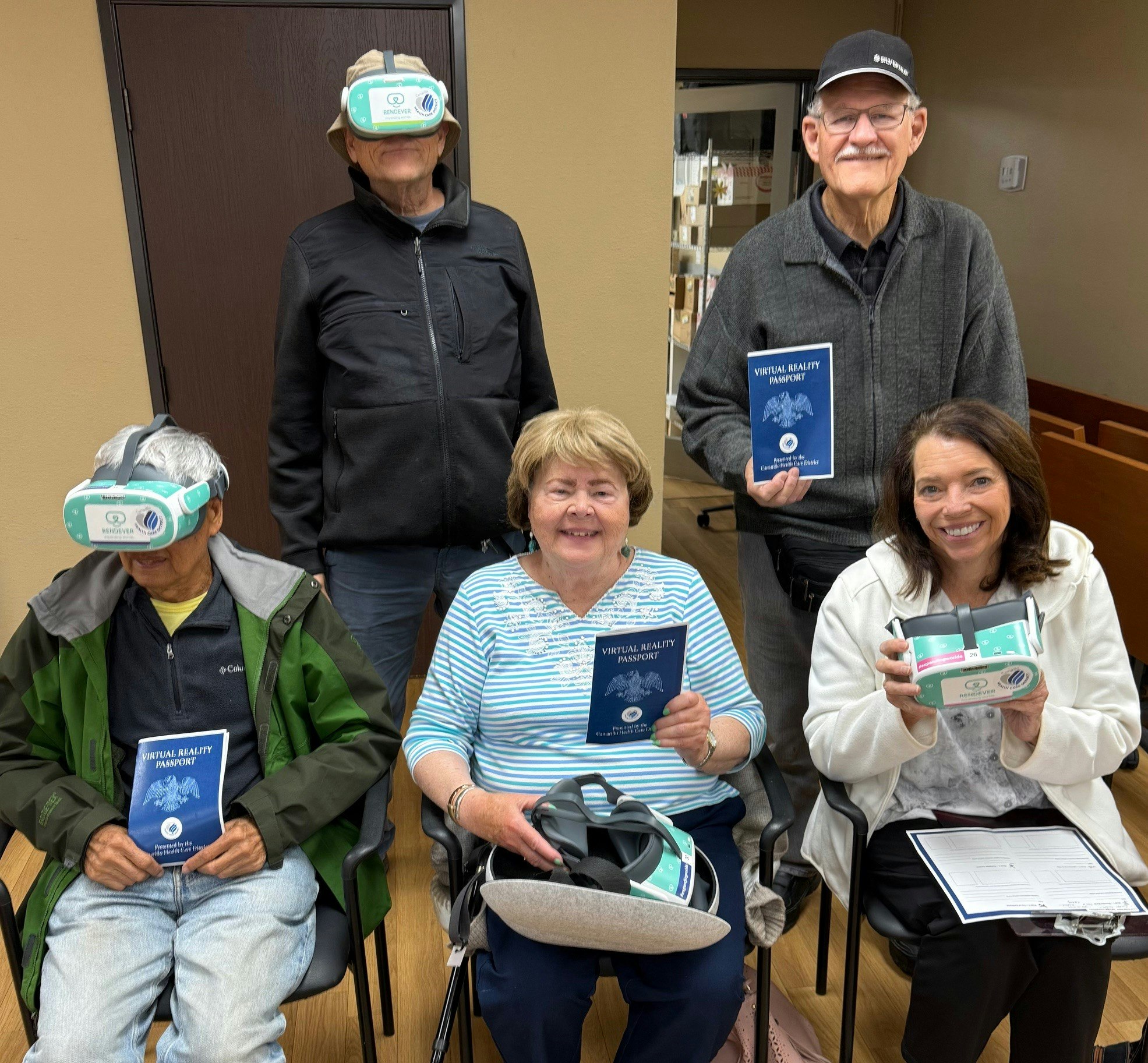 Five people with virtual reality glasses and "Virtual Reality Passport" booklets, smiling indoors.