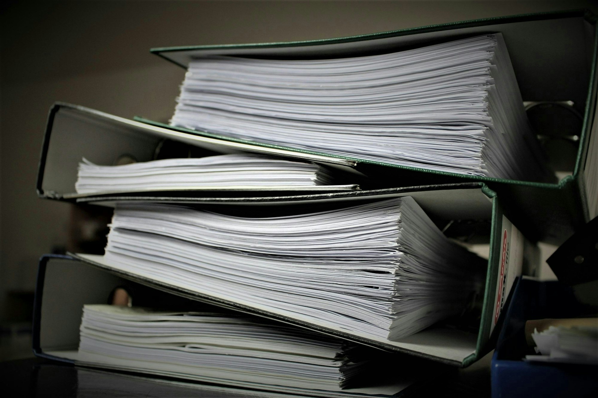 The image shows several stacked binders filled with sheets of paper, suggesting organized documents or reports.