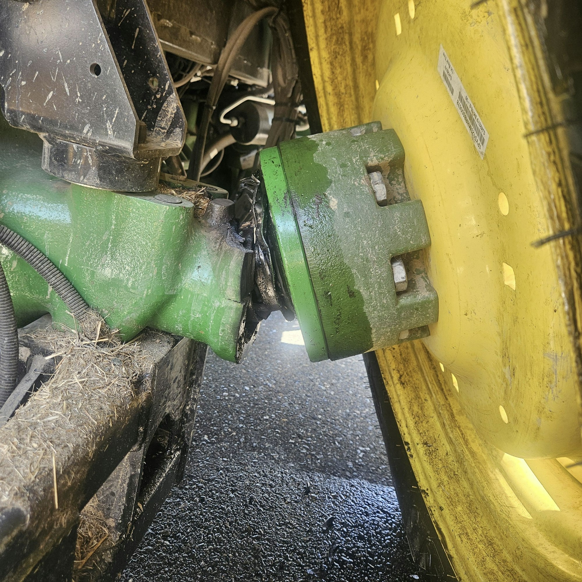The image shows a close-up of machinery components, possibly a green and yellow agricultural machine, with signs of wear and debris.