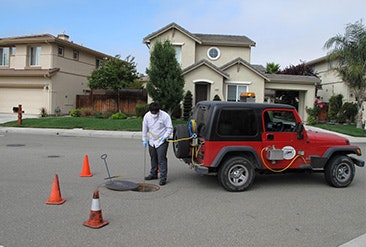 Jeep in street with person looking at a manhole
