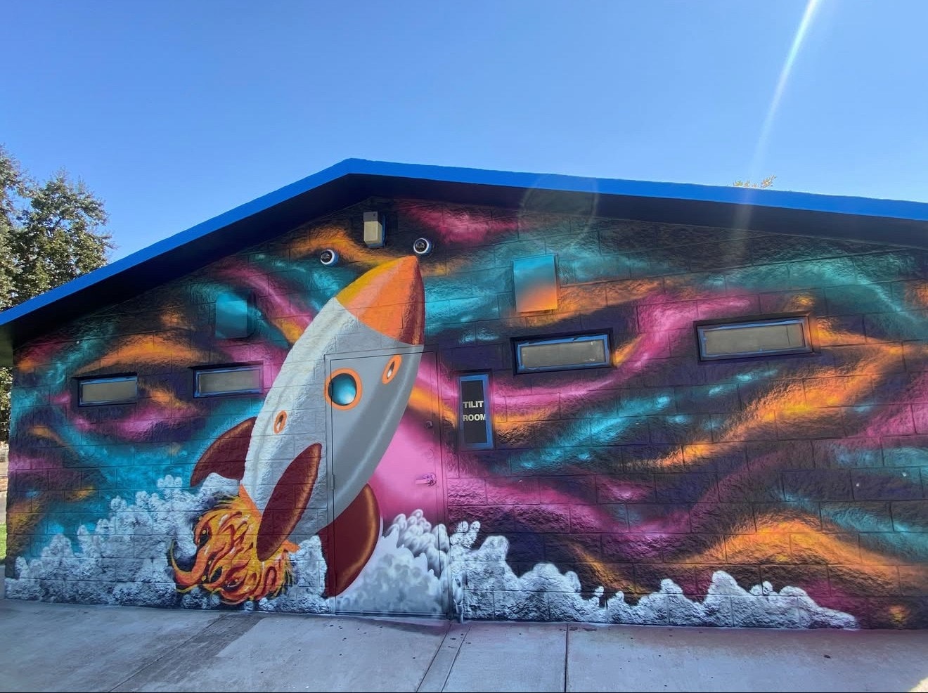 A mural of a rocket launching into space with colorful, swirling backgrounds on a building wall.