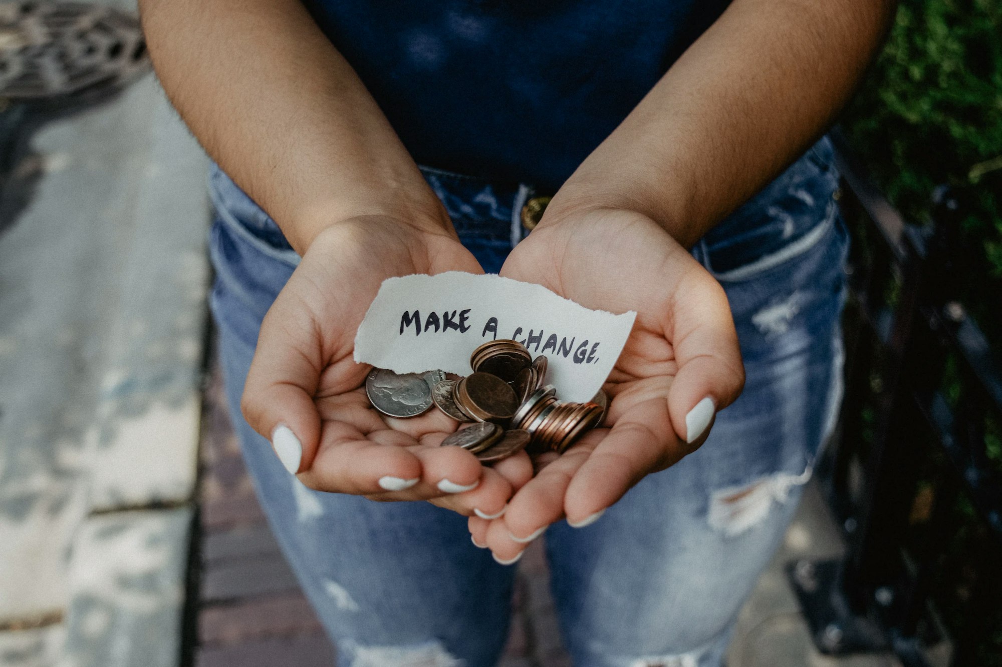 Woman holding a note that say's "Make a change" and some US coins.