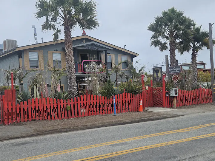 A colorful café and gallery called "Haute Enchilada," surrounded by palm trees and a bright red fence.